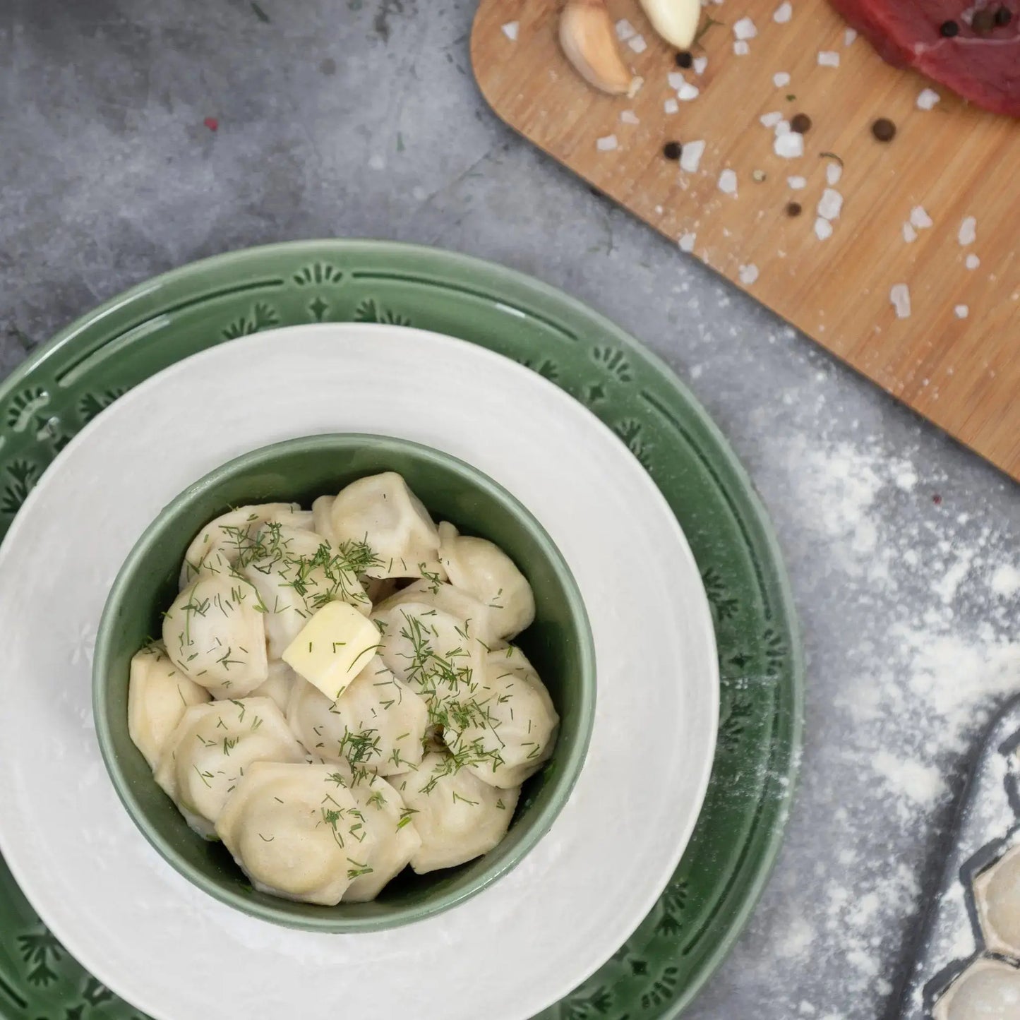 Top view of beef and pork pelmeni in bowl with butter and dill—Eastern European dumplings ready to serve.