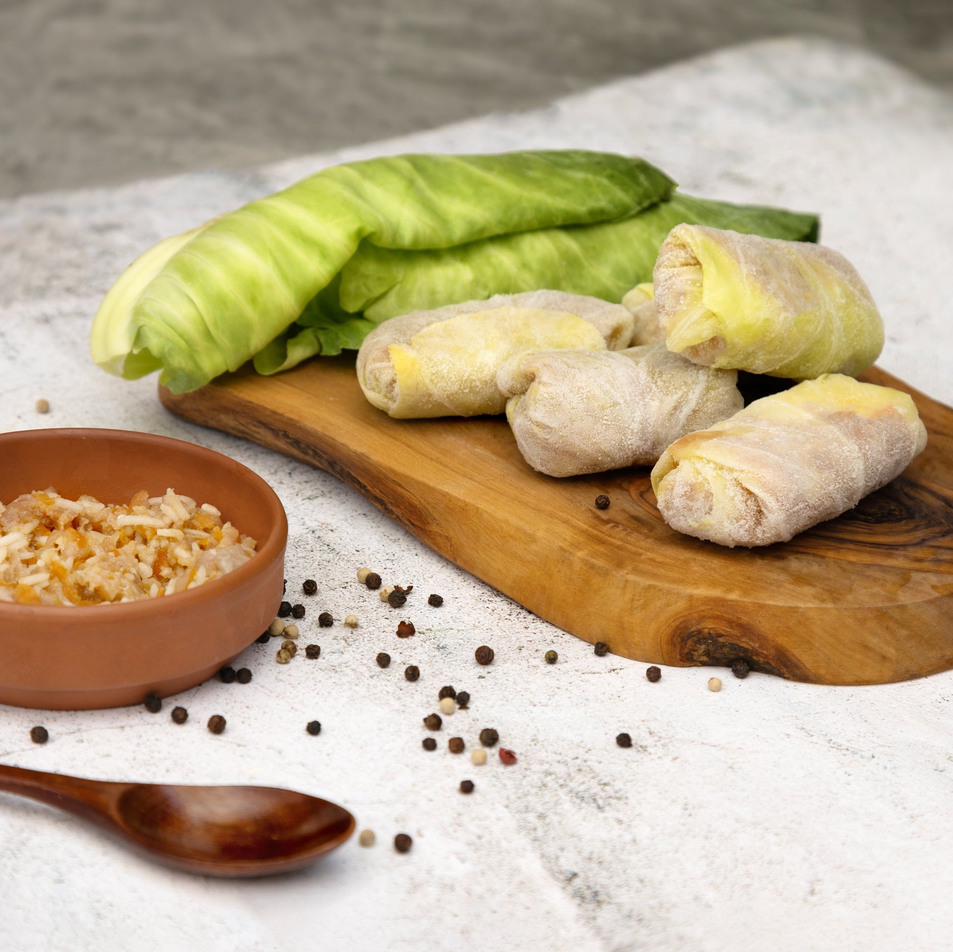 Uncooked golubtsi cabbage rolls on board with rice and pepper—Eastern European cabbage roll prep.