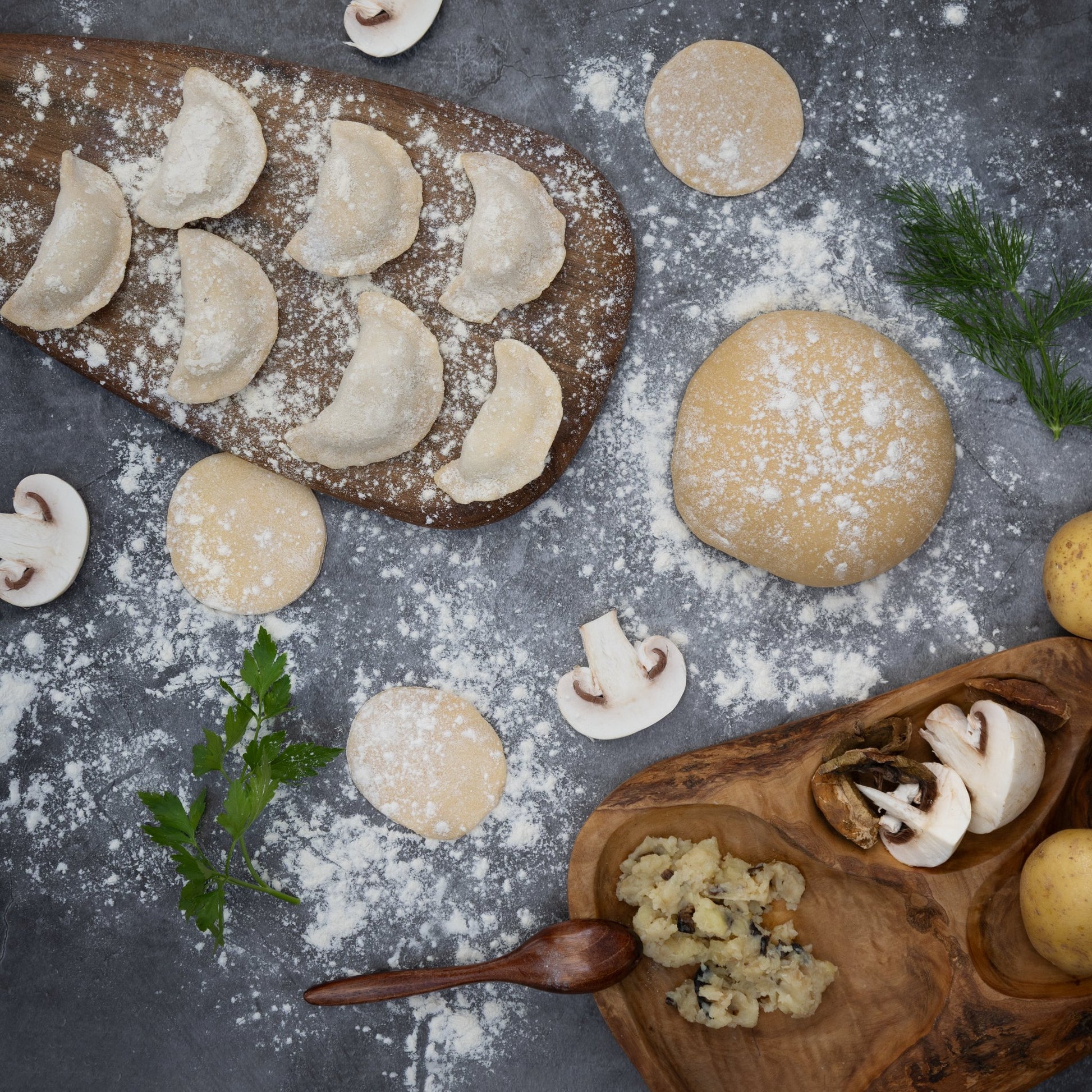 Uncooked varenyky dumplings with potato and mushrooms on floured board—traditional Eastern European prep.