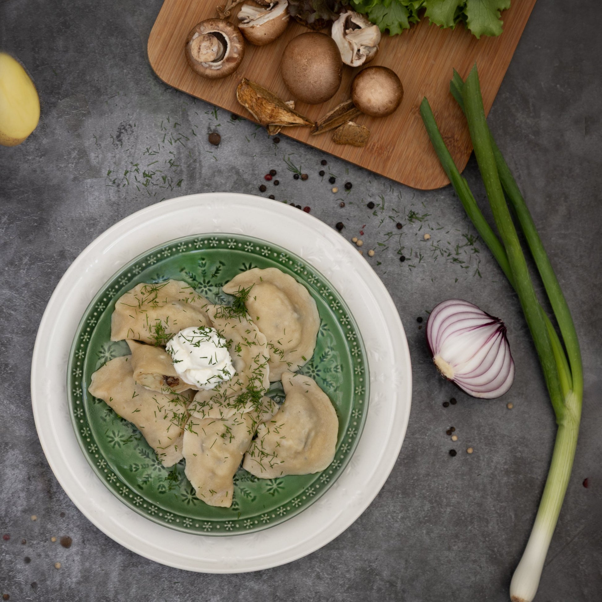 Top view of potato and mushroom varenyky with sour cream and dill—Eastern European dumpling comfort food.