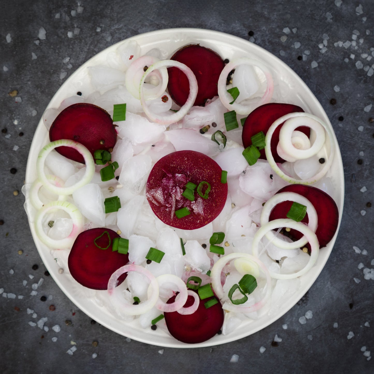 Fresh ingredients for Borscht including beetroot, onion, and herbs, presented on ice – showing the raw components of Rassoul's authentic frozen beetroot soup