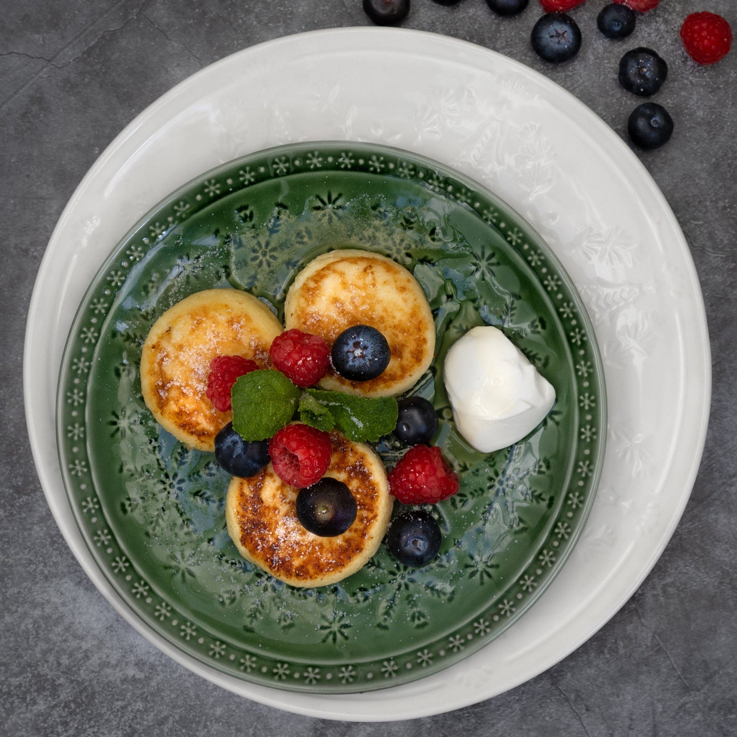 Cooked Syrnyky cottage cheese pancakes by Rassoul, served with fresh berries and sour cream – traditional Eastern European breakfast or dessert