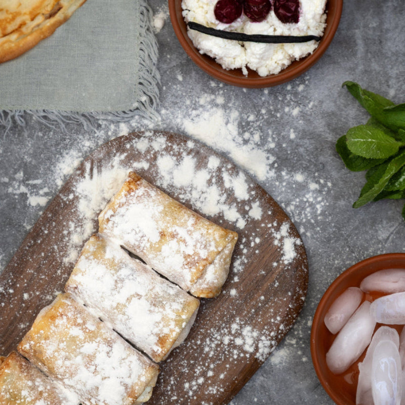 Handmade crepes with twarog cheese and sour cherry filling, dusted with powdered sugar on a wooden board, traditional Rassoul recipe.